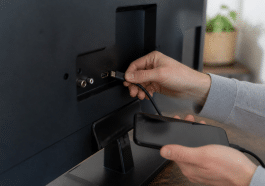 Main tenant cable HDMI entre smartphone et televiseur noir