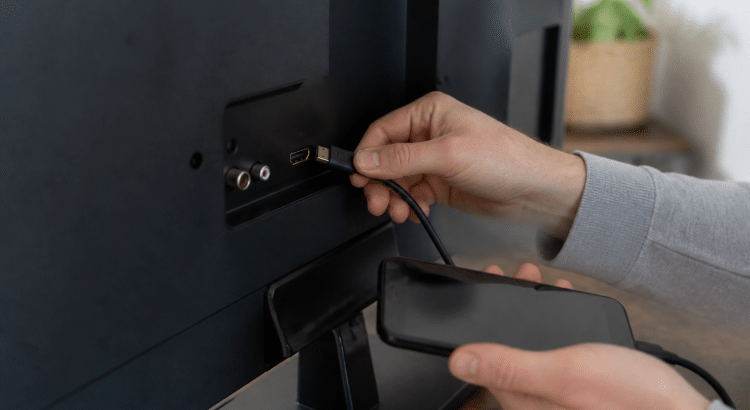 Main tenant cable HDMI entre smartphone et televiseur noir