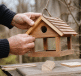 Mains construisant petite maison bois suspendue oiseaux