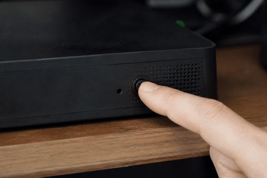 Doigt appuyant sur bouton reset box internet noire