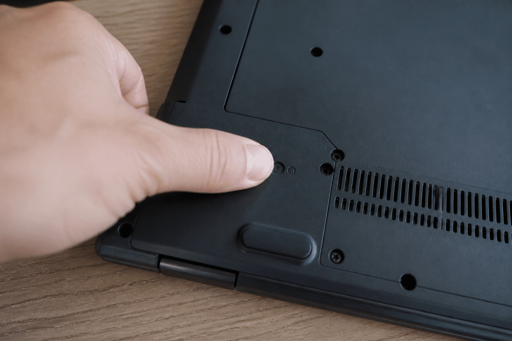 Doigt appuyant sur bouton de reinitialisation batterie ordinateur portable