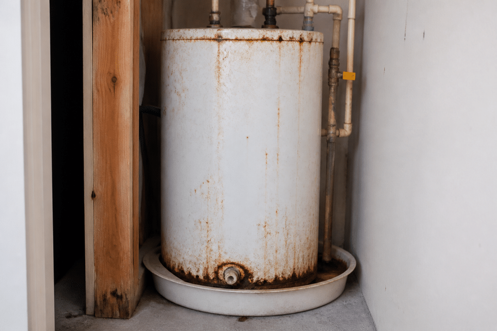 Chauffe-eau rouillé avec tuyaux et joints de plomberie visibles
