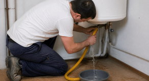 Homme vidant reservoir chauffe-eau avec tuyau d'evacuation